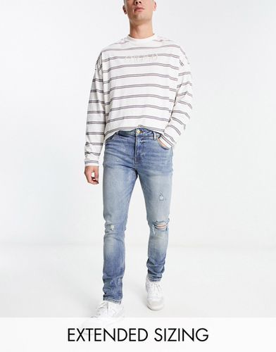 Jeans skinny lavaggio medio con strappi - ASOS DESIGN - Modalova