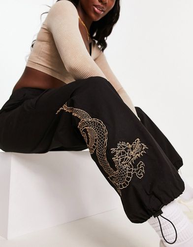 Pantaloni neri stile paracadutista con drago ricamato - New Look - Modalova