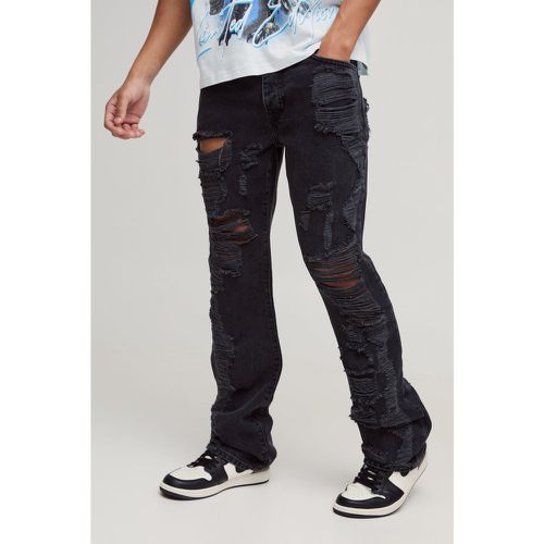 Jeans Slim Fit in denim rigido a zampa con strappi all over - boohoo - Modalova