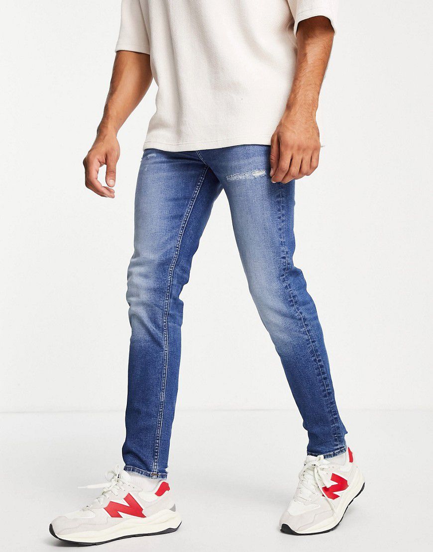 Jeans skinny lavaggio scuro con fondo invecchiato - ASOS DESIGN - Modalova